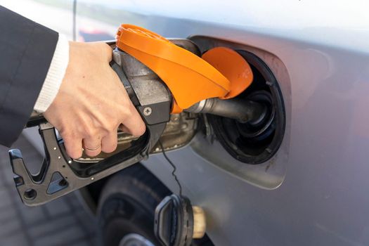 a woman's hand holds a refueling gun in the neck of the tank of the car. the girl refuels the car. High quality photo