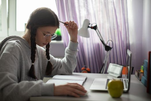 A student is thinking and thinking about how to solve a complicated assignment she received from school to do at home. A diligent student. Remote learning at home.