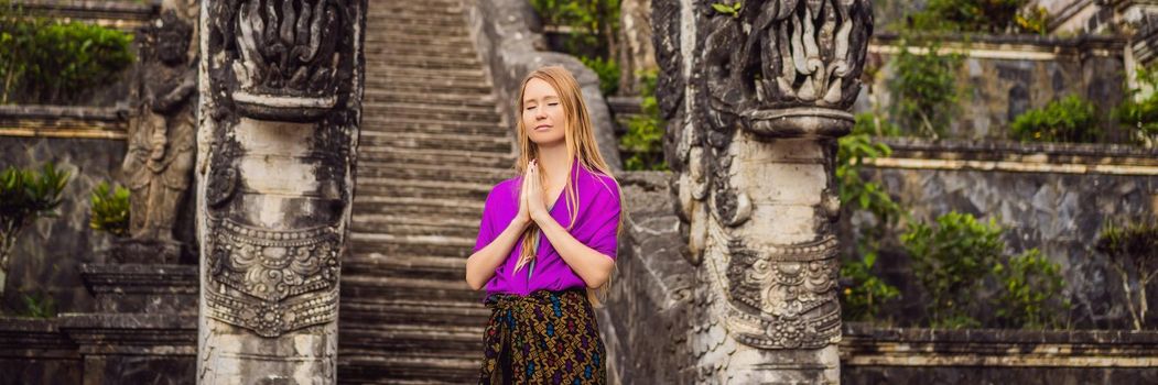 BANNER, LONG FORMAT Young woman tourist on background of Three stone ladders in beautiful Pura Lempuyang Luhur temple. Summer landscape with stairs to temple. Paduraksa portals marking entrance to middle sanctum jaba tengah of Pura Penataran Agung, Bali.