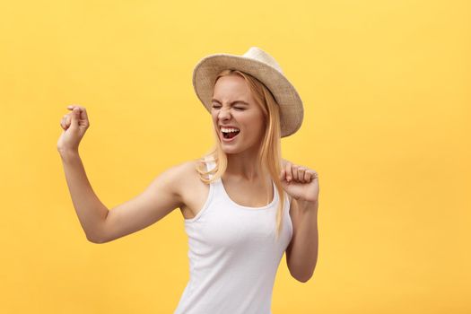 Young beautiful woman dancing in studio isolated on yellow background.