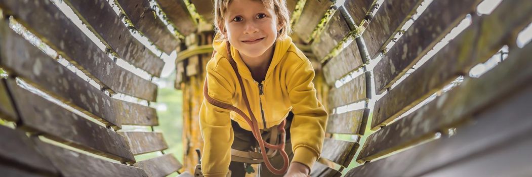 Little boy in a rope park. Active physical recreation of the child in the fresh air in the park. Training for children. BANNER, LONG FORMAT