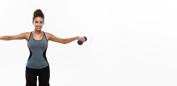 Healthy and Fitness concept - Beautiful American African lady in fitness clothes workout with dumbbell. Isolated on white background