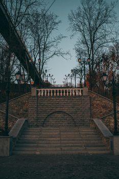 Park area with a stone arch and steps along the slope. Park landscape with a bridge in the background. Beautiful landscape from the filter