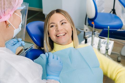 The girl smiles at the dentist and looks at her.