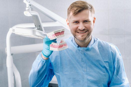 A model of a human jaw with teeth and a toothbrush in the dentist's hand.