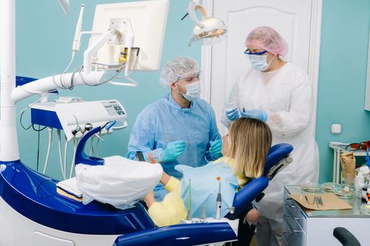 A female patient in dental glasses treats teeth at the dentist with ultraviolet light. dental fillings.