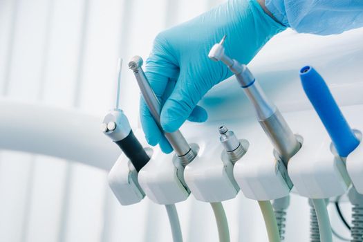 a dentist wearing gloves in the dental office holds a tool before working.