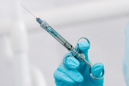 close-up of a dentist's hand holding an injection syringe for a patient in the office.