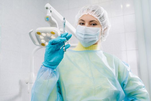 A masked dentist holds an injection syringe for a patient in the office.