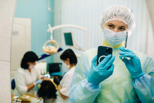 the dentist in a protective mask stands next to the patient and takes a photo after work.