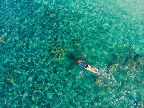 Happy woman in snorkeling mask dive underwater with tropical fishes in coral reef sea pool. Travel lifestyle, water sport outdoor adventure, swimming lessons on summer beach holiday. Aerial view from the drone.