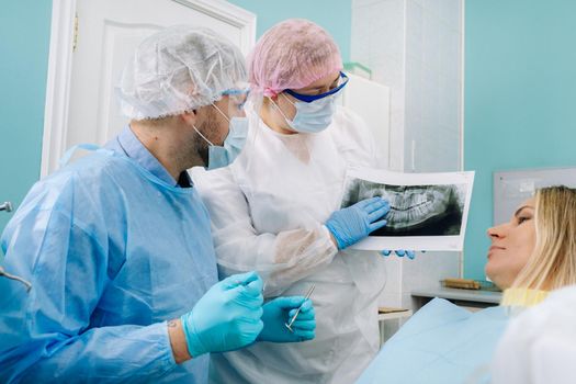 Dentist explaining the details of the X-ray to his patient in the office.