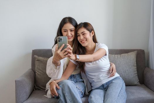 lgbtq, lgbt concept, homosexuality, portrait of two asian women enjoying together and showing love for each other while using smartphone mobile to take selfies.