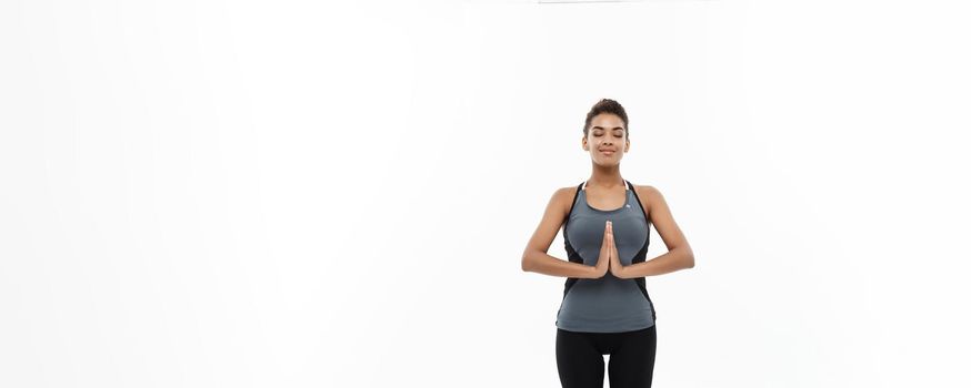 Healthy and Fitness concept - Beautiful American African lady in fitness clothing doing yoga and meditation. Isolated on white background