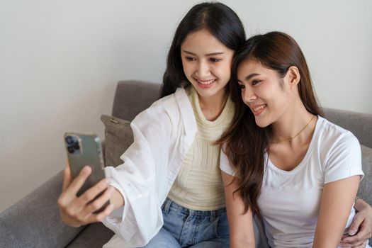 lgbtq, lgbt concept, homosexuality, portrait of two asian women enjoying together and showing love for each other while using smartphone mobile to take selfies.