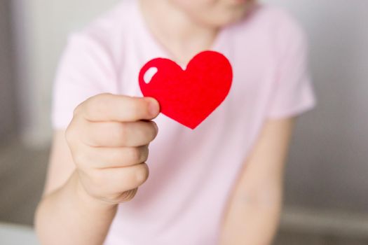 A blogger girl makes a felt craft for Valentine's Day in the shape of a heart. The concept of children's creativity and handmade.