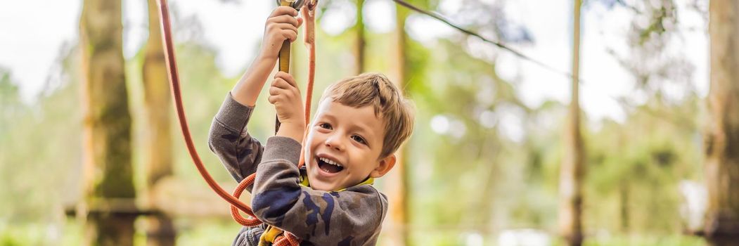 Little boy in a rope park. Active physical recreation of the child in the fresh air in the park. Training for children. BANNER, LONG FORMAT