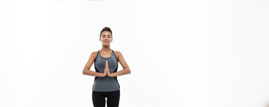 Healthy and Fitness concept - Beautiful American African lady in fitness clothing doing yoga and meditation. Isolated on white background