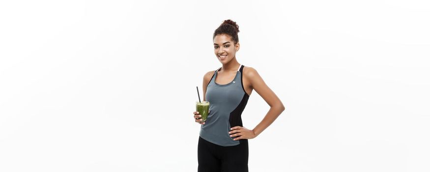 Healthy and Fitness concept - beautiful African American girl in sport clothes holding plastic water bottle after workout. Isolated on white studio background.