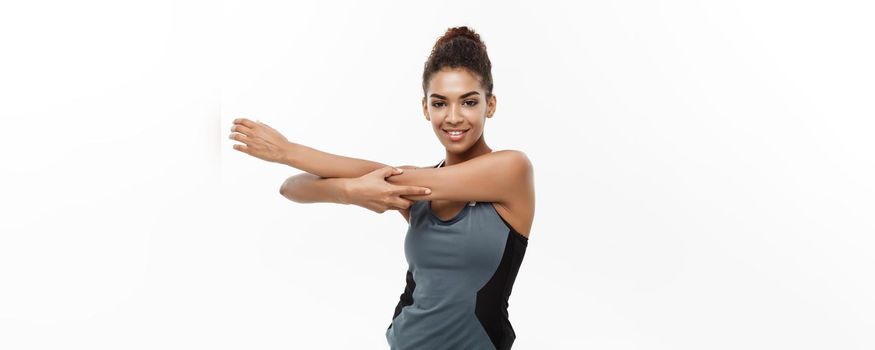 Sport, training, lifestyle and Fitness concept - portrait of beautiful happy African American woman stretching hands. Isolated on white studio background