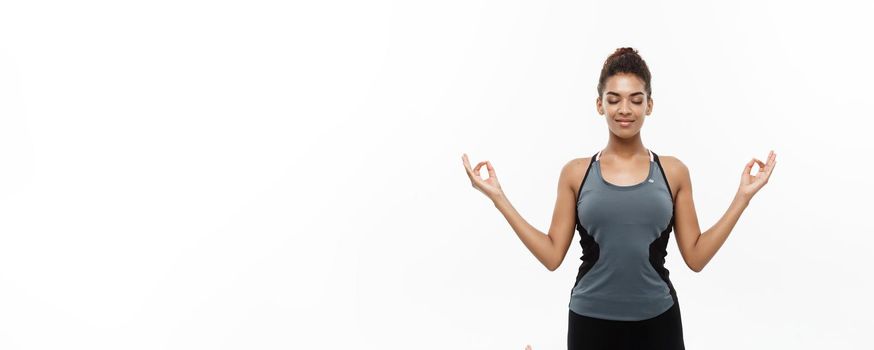 Healthy and Fitness concept - Beautiful American African lady in fitness clothing doing yoga and meditation. Isolated on white background