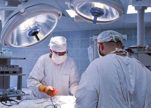 Group of surgeons in operating room with surgery equipment. Modern medical background. In surgery.