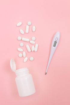 White Pills or Tablets with Electronic Thermometer on Pink Background. Pharmaceutical Industry and Medicinal Products