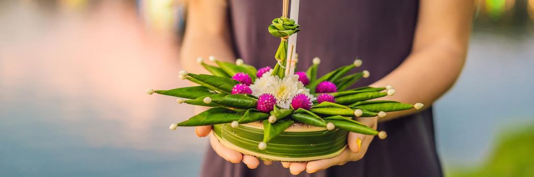 BANNER, LONG FORMAT A female tourist holds the Loy Krathong in her hands and is about to launch it into the water. Loy Krathong festival, People buy flowers and candle to light and float on water to celebrate the Loy Krathong festival in Thailand.