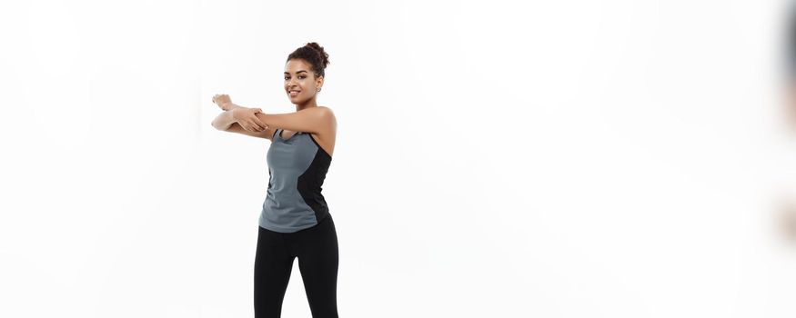 Sport, training, lifestyle and Fitness concept - Full-length portrait of beautiful happy African American woman stretching hands. Isolated on white studio background