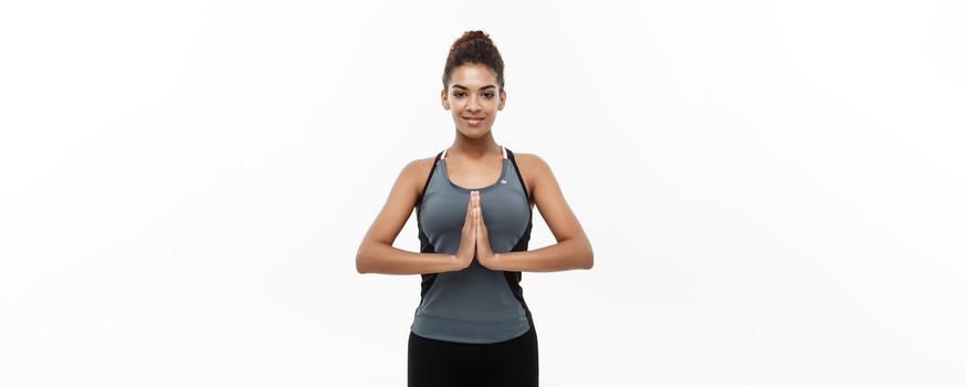 Healthy and Fitness concept - Beautiful American African lady in fitness clothing doing yoga and meditation. Isolated on white background