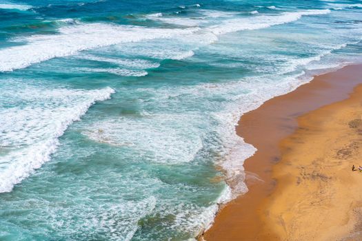 Aerial view of tropical sandy beach and ocean with turquoise water with waves. Sunny day on Atlantic ocean beach in Portugal