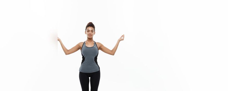 Healthy and Fitness concept - Beautiful American African lady in fitness clothing doing yoga and meditation. Isolated on white background