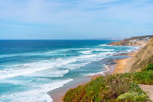 Aerial view of tropical sandy beach and ocean with turquoise water with waves. Sunny day on Atlantic ocean beach in Portugal