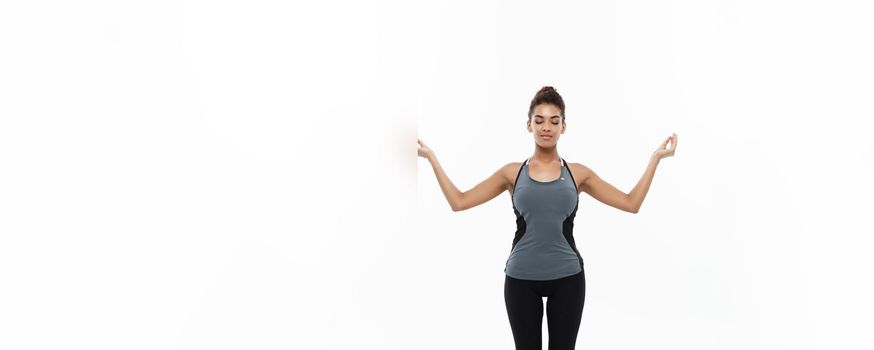 Healthy and Fitness concept - Beautiful American African lady in fitness clothing doing yoga and meditation. Isolated on white background