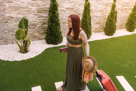 young girl arriving with her luggage at the reception of her summer holiday hotel. tourist arriving at her holiday destination. tropical resort. outside, natural sunlight, businesswoman arriving at her holiday destination.