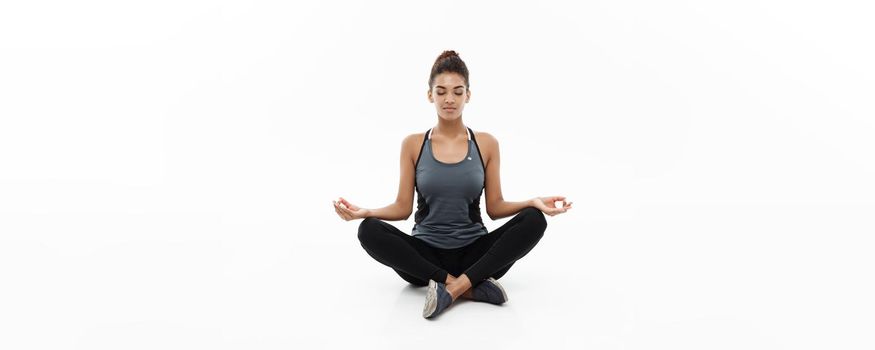 Healthy and Fitness concept - Beautiful American African lady in fitness clothing doing yoga and meditation. Isolated on white background