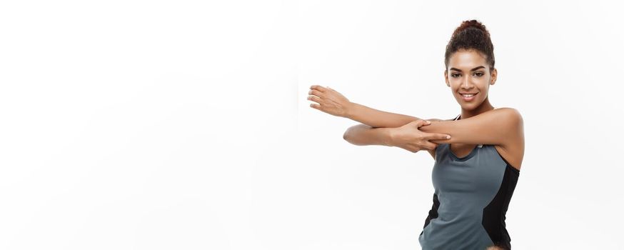 Sport, training, lifestyle and Fitness concept - portrait of beautiful happy African American woman stretching hands. Isolated on white studio background