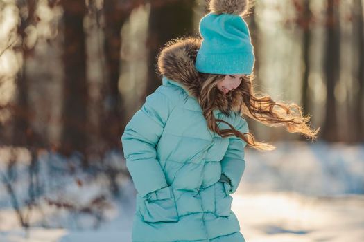 happy girl in turquoise jacket and hat