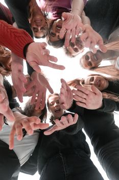 close up. happy young people standing in a circle and showing thumbs up