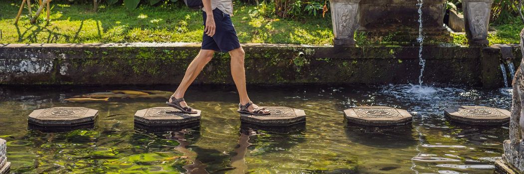 Young man tourist in Taman Tirtagangga, Water palace, Water park, Bali Indonesia. BANNER, LONG FORMAT