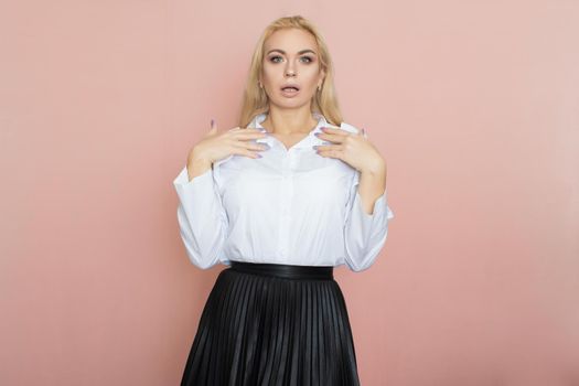 Beauty, fashion portrait. Elegant business style. Portrait of a beautiful blonde woman in white blouse and black skirt posing at studio on a pink background.