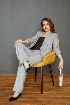 A girl in a business suit, sitting on a chair