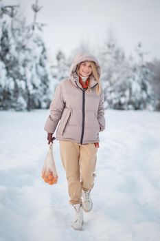 A model girl walking through a snow-covered forest, a demonstration of clothes.