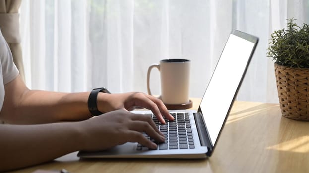 Cropped shot casual young woman sitting in bright living room and using computer laptop.