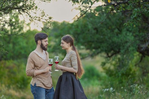 young couple drinking standing drinking wine from glasses being in nature