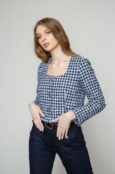 A girl in a denim suit standing on a studio background. A model in a blue suit