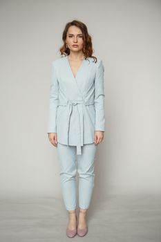 A model in a blue pantsuit on a studio background.