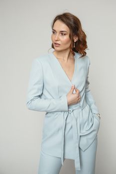 A model in a blue pantsuit on a studio background.