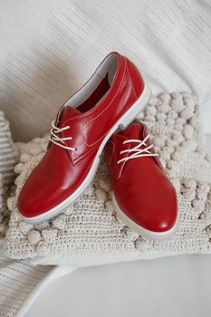 Red shoes with white laces, which are on a white knitted scarf