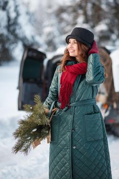 A girl in a winter forest with a paper bag containing spruce branches.